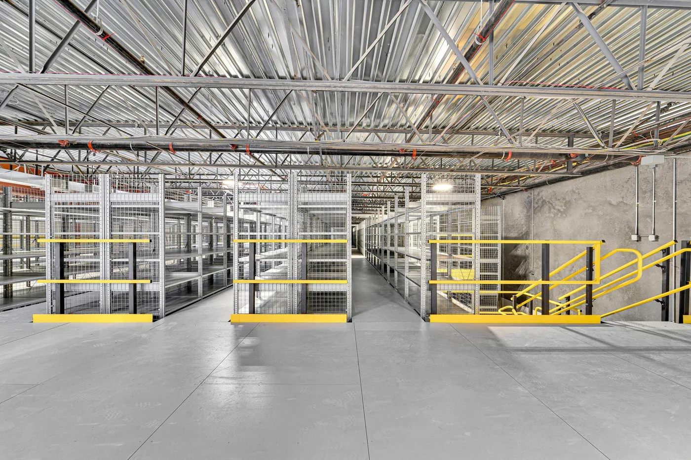 Wildeck steel mezzanine platform with resin board decking and yellow perimeter guardrail in a warehouse