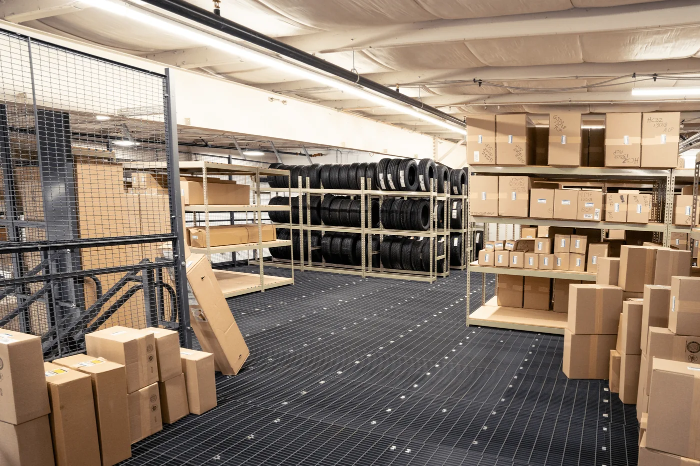Caged parts storage area with shelving and tire storage on a mezzanine deck