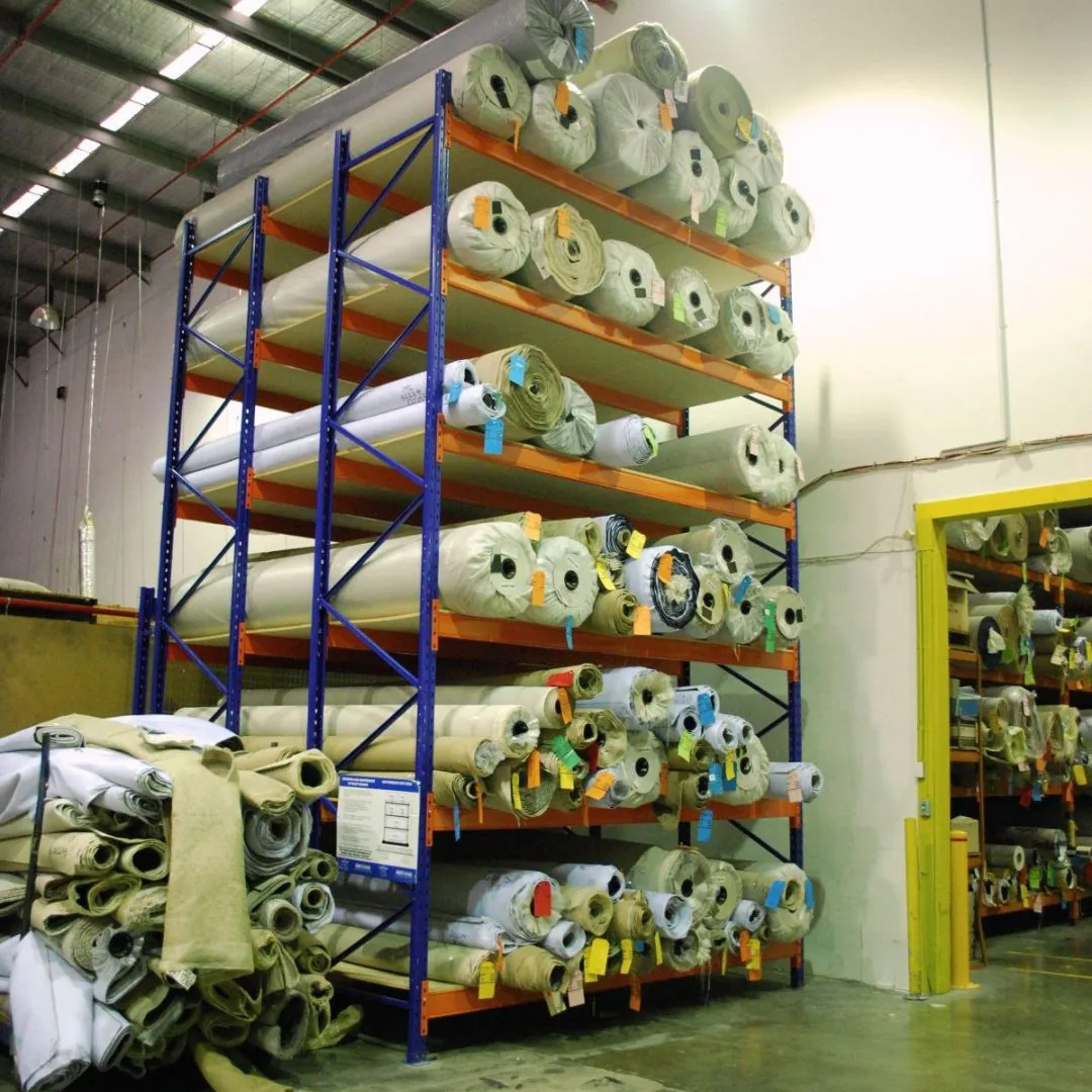 Horizontal roll rack storing rolls of material in a warehouse aisle
