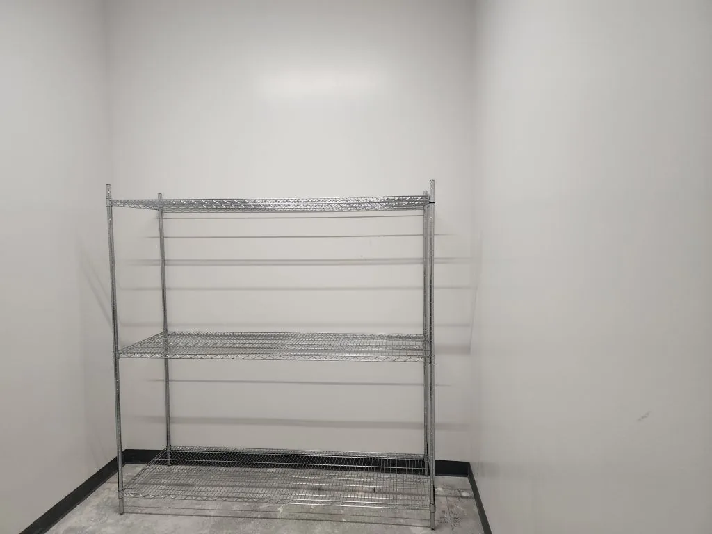 Adjustable steel wall shelving loaded with organized supply bins along a storeroom wall