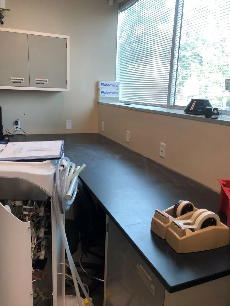 Laboratory counter with computer equipment and wall cabinets beside a window