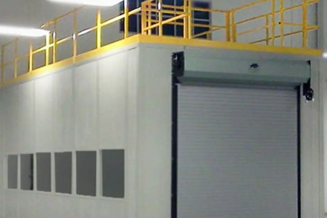 Modular warehouse office with a roll-up door and a guarded storage roof above
