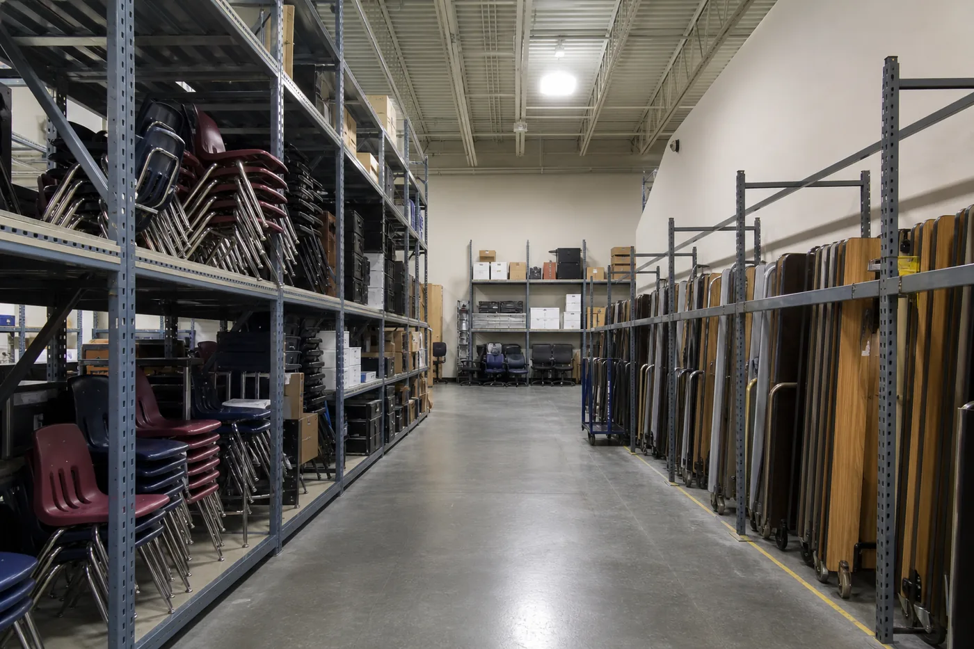 School district storage room with classroom chairs and equipment on wide-span shelving