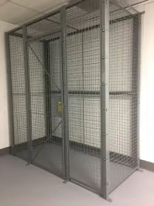 Finished gray wire mesh security cage with a locking hinged door in an interior facility