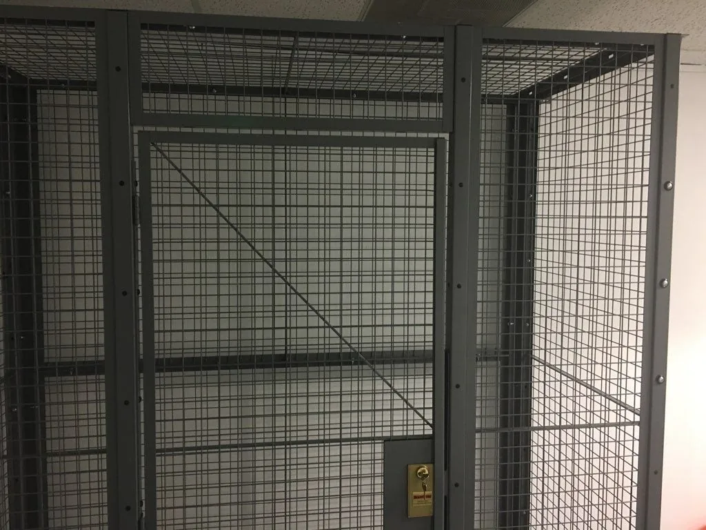Welded wire mesh security partition enclosing a storage area inside a distribution warehouse