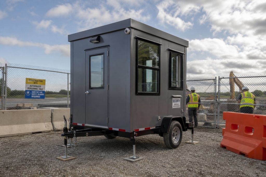 Trailer-mounted guard booth set up at a construction site entrance on leveling jacks