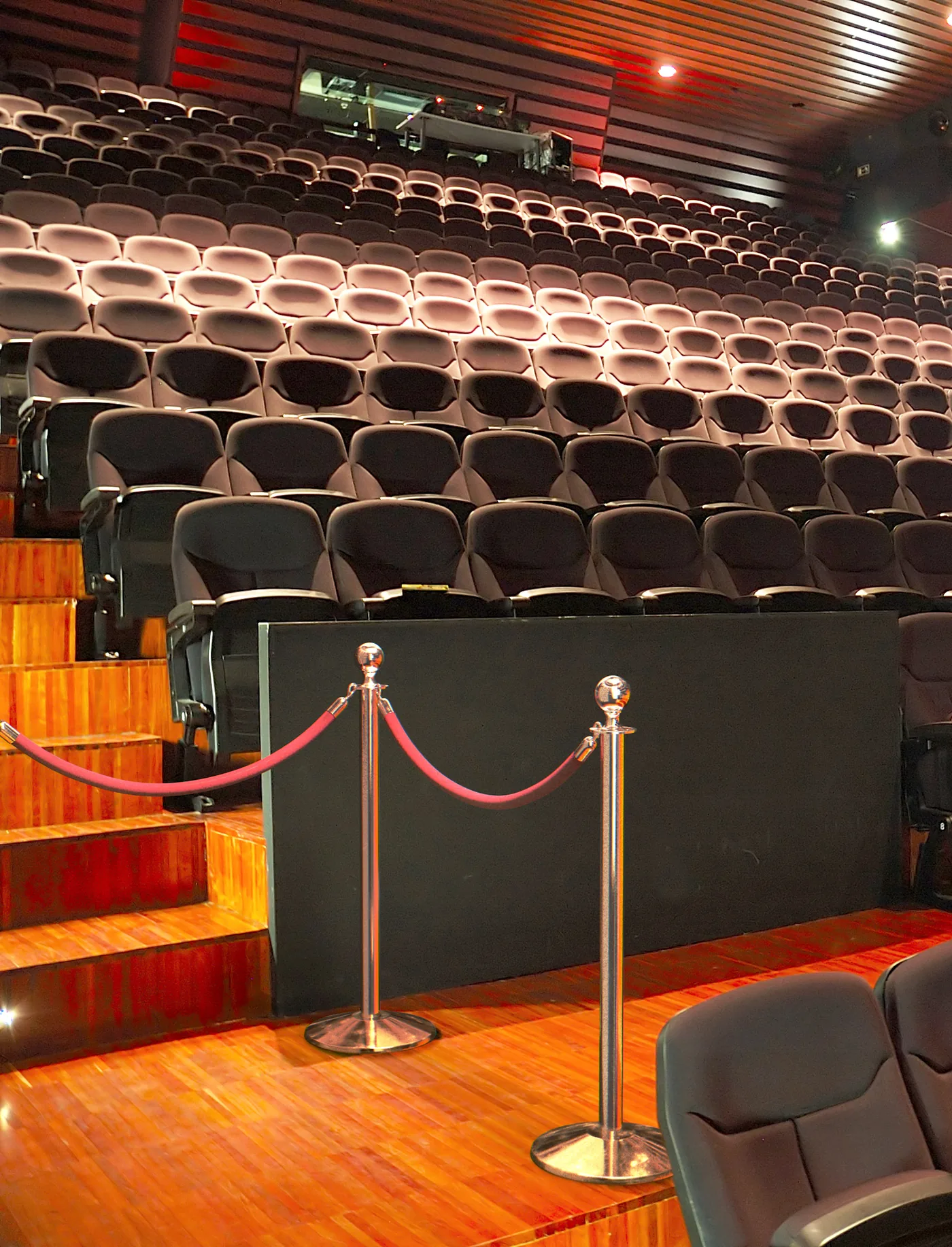Polished classic post and rope stanchions protecting a theater stage in front of audience seating
