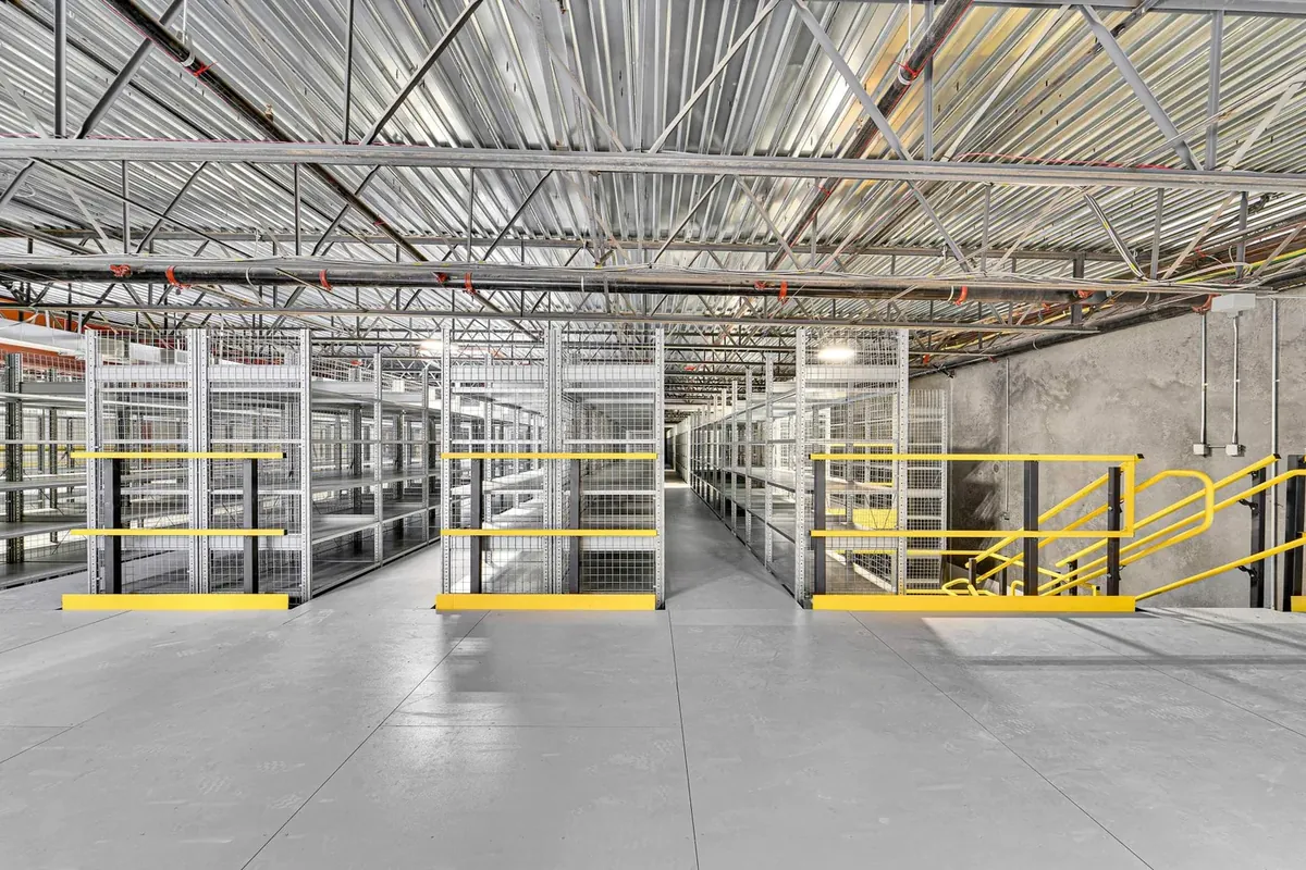Mezzanine deck with resin board decking and yellow guardrail inside an industrial facility