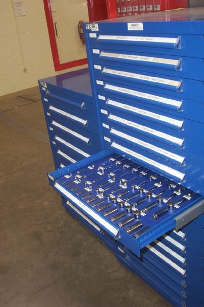 Blue modular drawer cabinets with an open drawer of sockets organized by dividers in a maintenance area