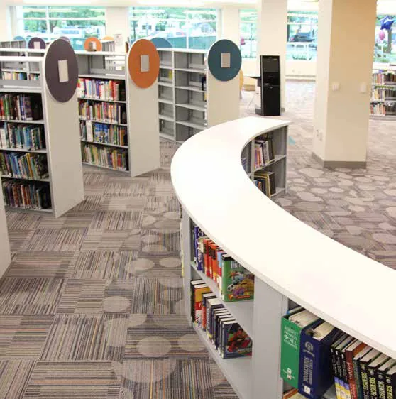 Aurora library shelving ranges with colored end panels behind a curved service desk