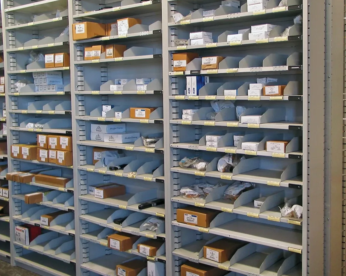 Rows of gray Borroughs Flexi-Bin shelving with sliding dividers holding boxed and bagged parts