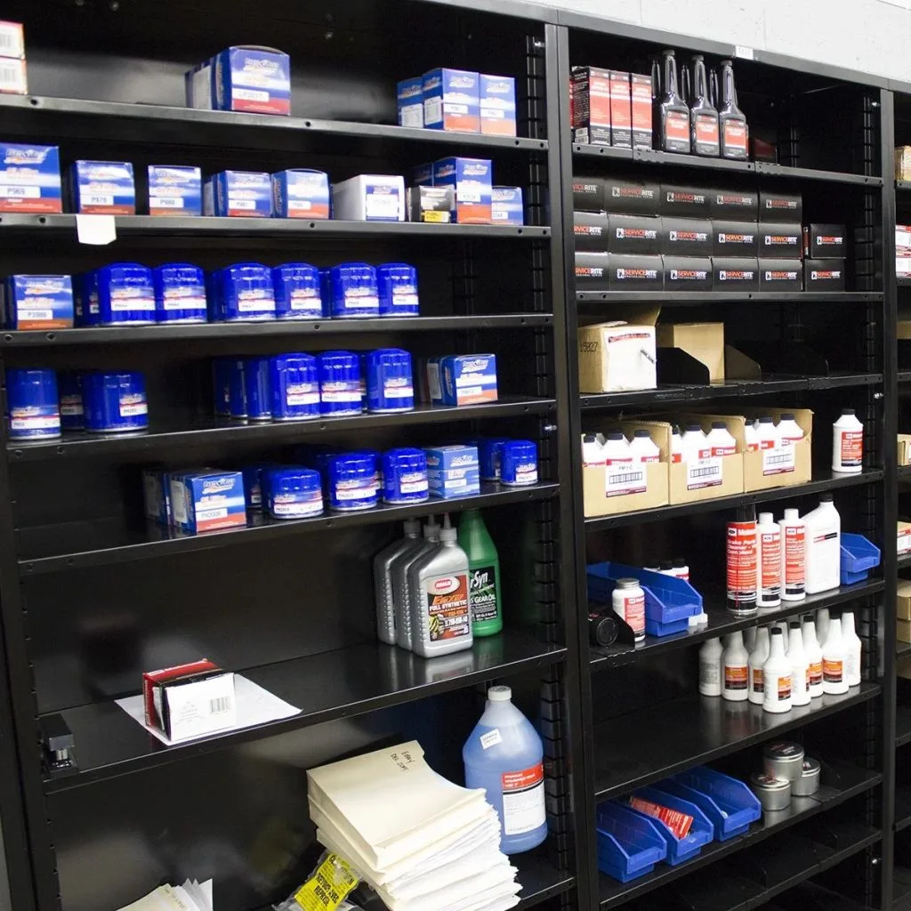 Enclosed steel shelving holding boxed automotive parts and fluids in an organized parts room.