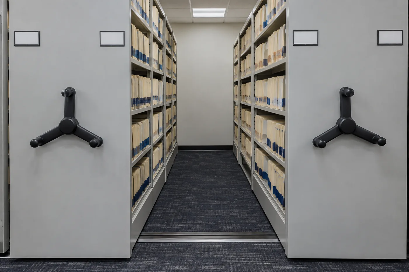 Open mobile shelving aisle in a college registrar file room with end-tab student file folders on both carriages