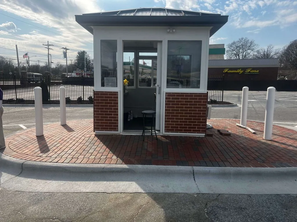 Custom brick-clad guard booth with bollards at a facility entrance visitor lane