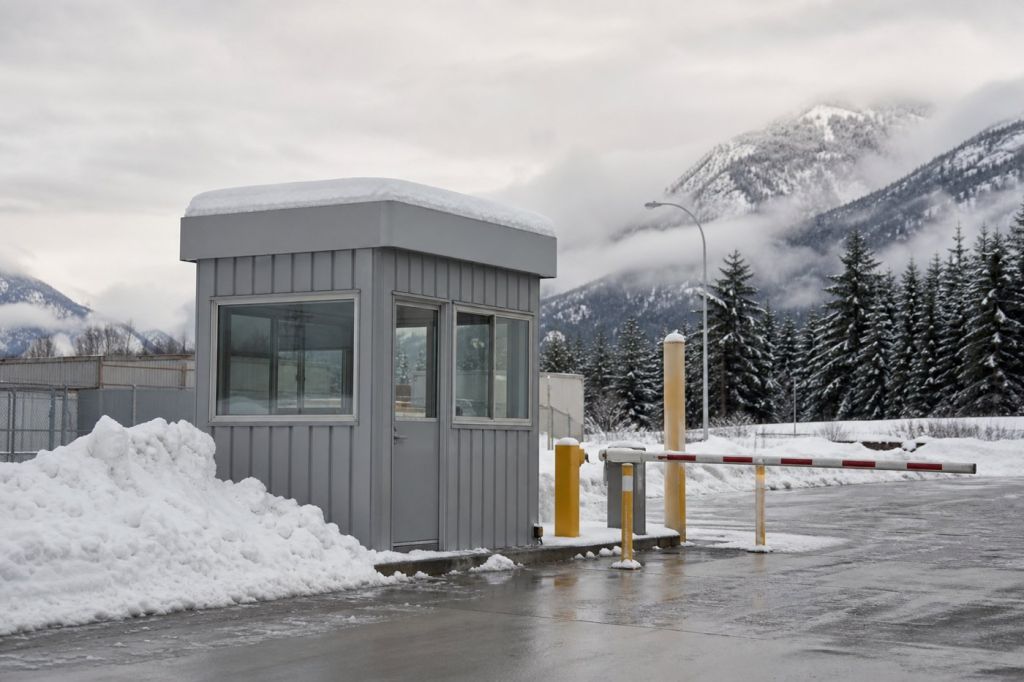 Steel guard booth with snow accumulated on its roof at a Utah industrial gate in winter