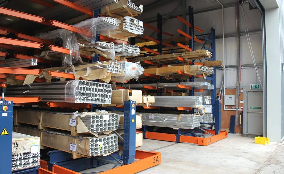 Interlake Mecalux cantilever rack rows holding long aluminum and steel profiles across the arms in a manufacturer's shop