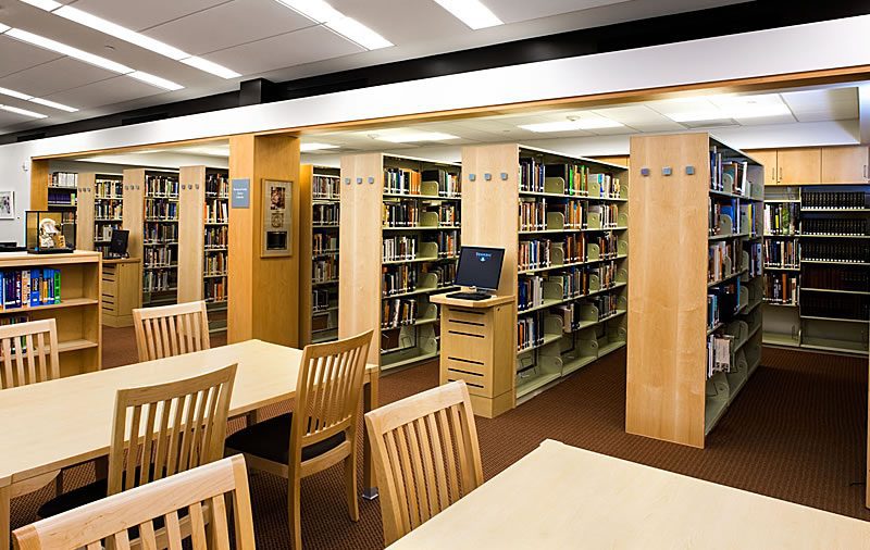 Cantilever library shelving with wood end panels and reading tables in a school library reading room