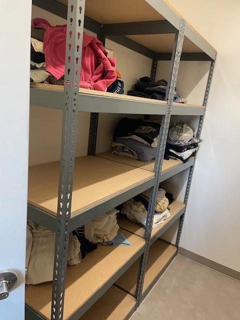 Boltless shelving unit with double rivet beams and particle board levels storing folded clothing, Ogden, Utah
