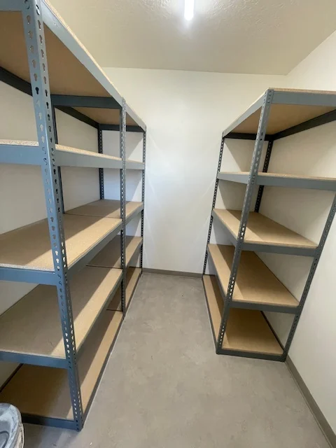 Boltless shelving with five particle board levels lining both sides of a narrow storage room in Ogden, Utah