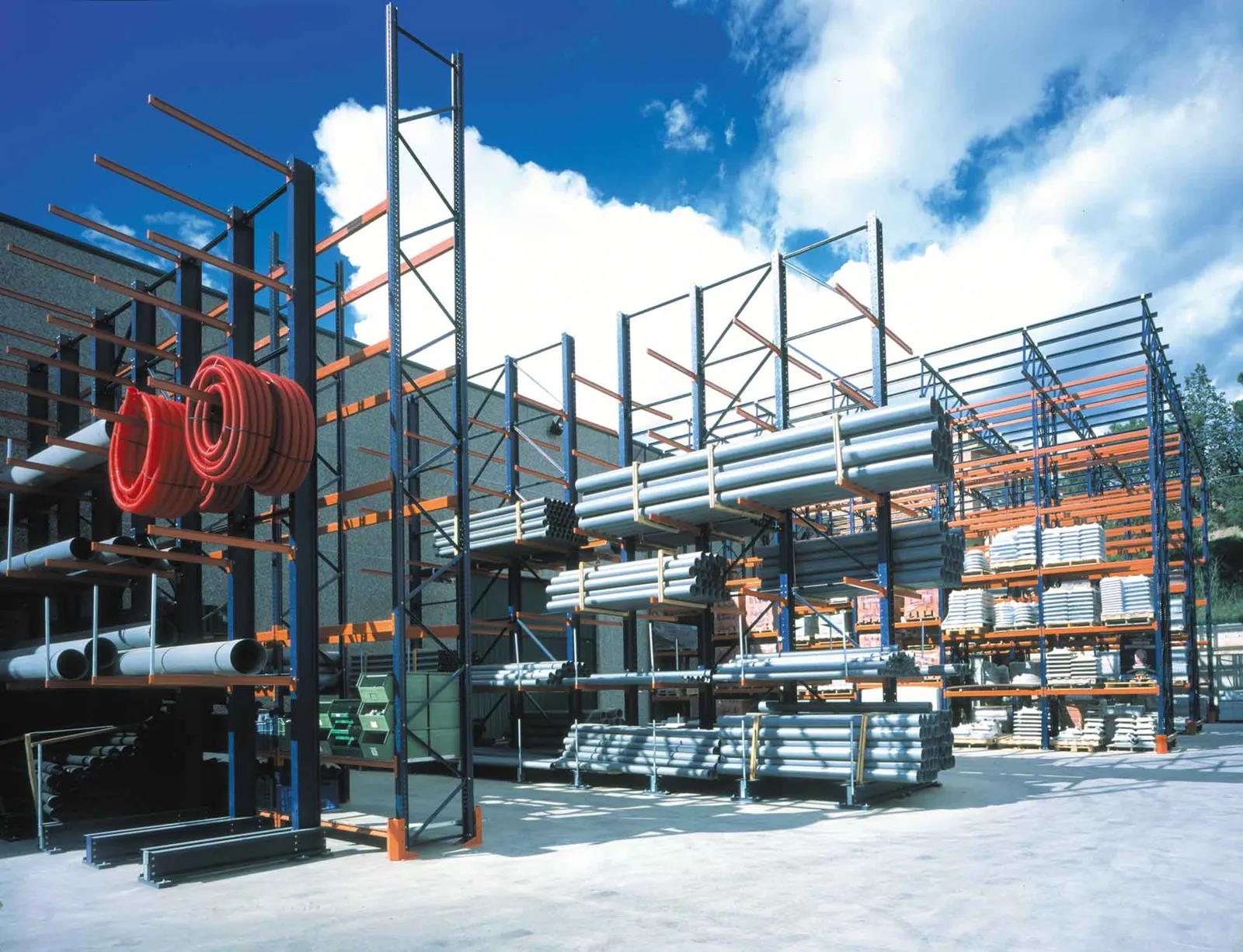 Tall outdoor cantilever racks holding pipe and coiled tube in an open storage yard