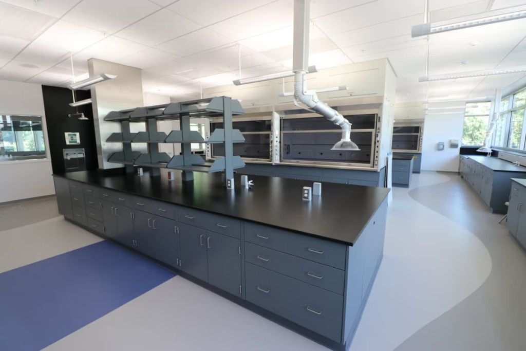 ICI Scientific laboratory island with dark countertops, blue-gray cabinets and overhead service shelving