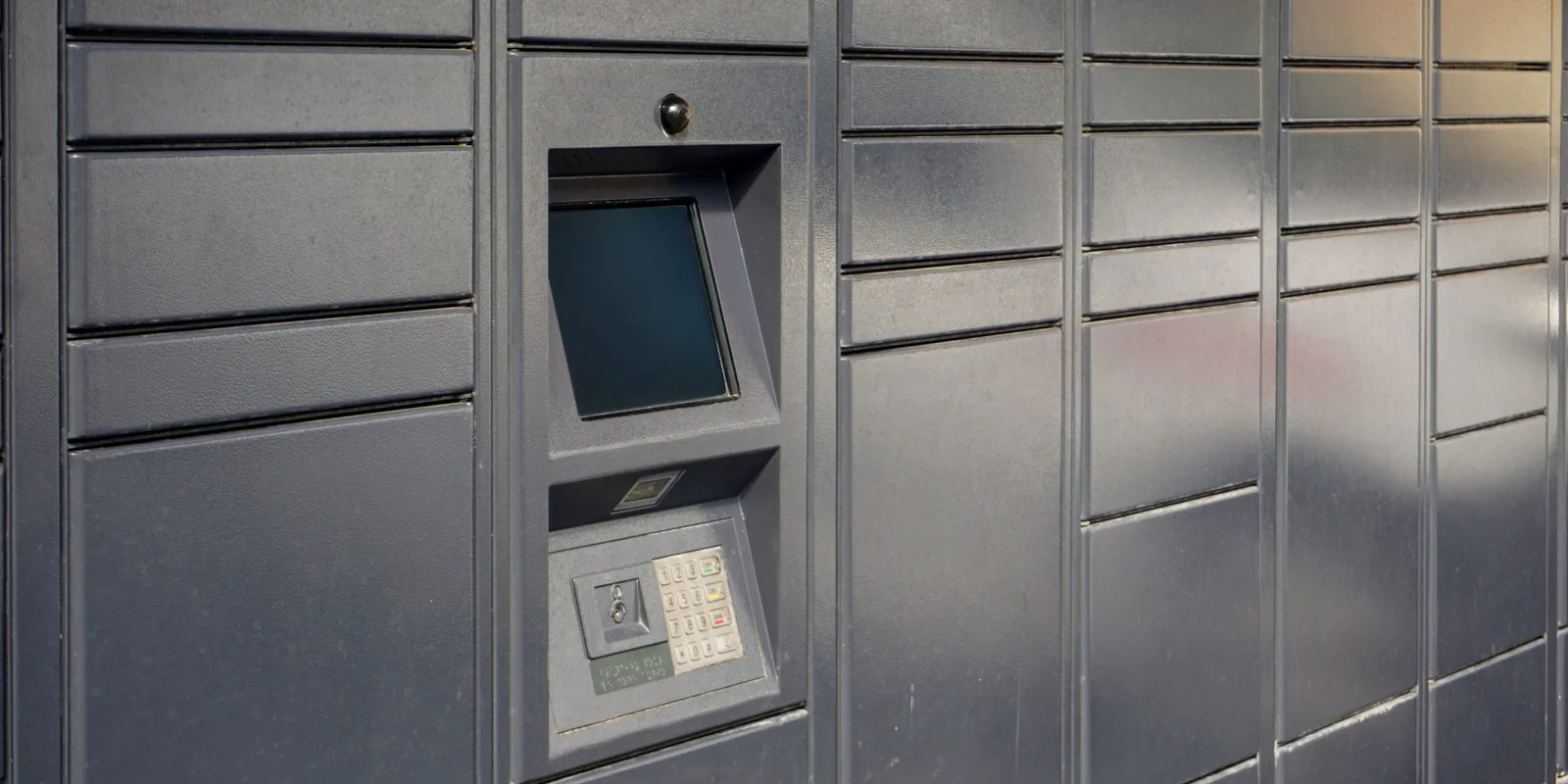 Close-up of a smart parcel locker kiosk with touchscreen, barcode scanner, keypad and camera used for resident package pickup