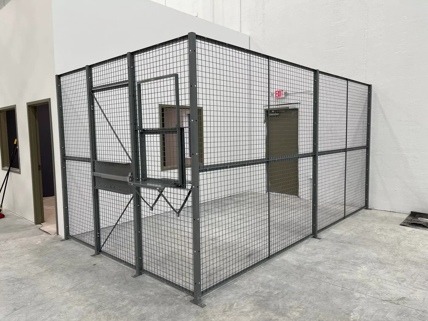 Wire mesh enclosure with a fold-down service shelf, pass window and exit sign above the door