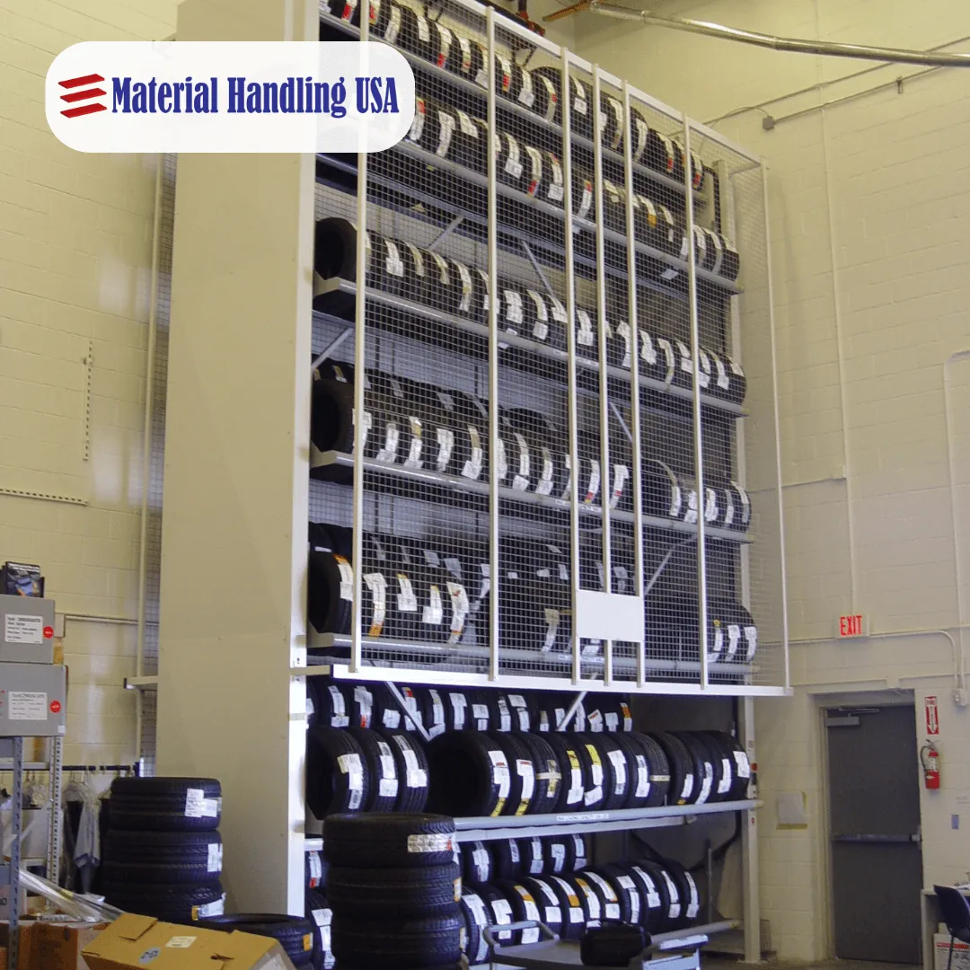 Tall vertical tire carousel with rows of tire carriers behind wire guarding and a floor level access opening