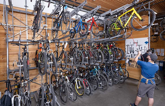 Technician accessing an overhead bicycle on a Vidir Bicycle Merchandising System rack in a retail bike shop