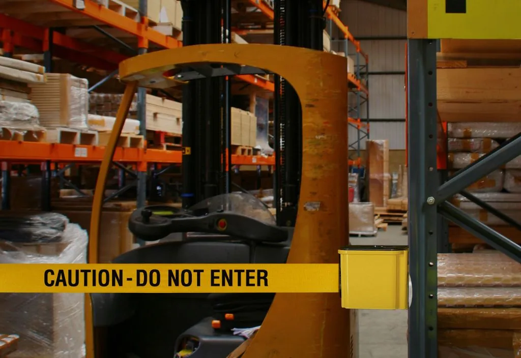 Wall-mounted retractable belt with a yellow CAUTION DO NOT ENTER belt closing a warehouse aisle