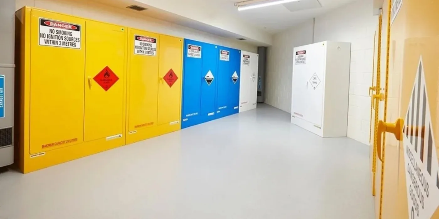 Row of flammable, corrosive and general chemical storage cabinets along a storage room wall