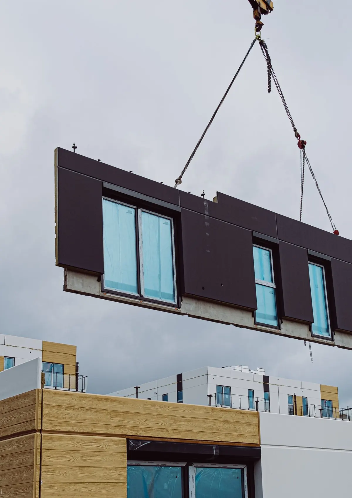 Crane lifting a prefabricated building module with windows into position