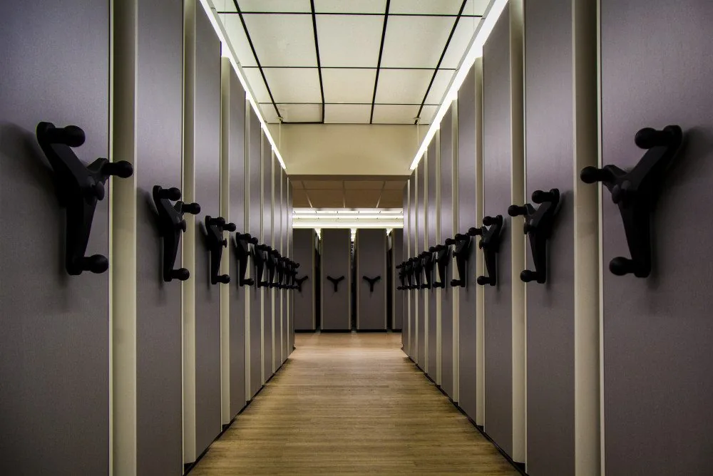 Open access aisle inside a Spacefile high-density mobile shelving system with drive handwheels on each end panel