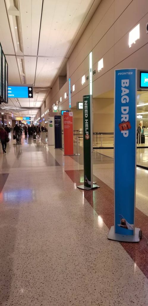 Row of tall freestanding sign towers marking bag drop and check-in positions along airline counters