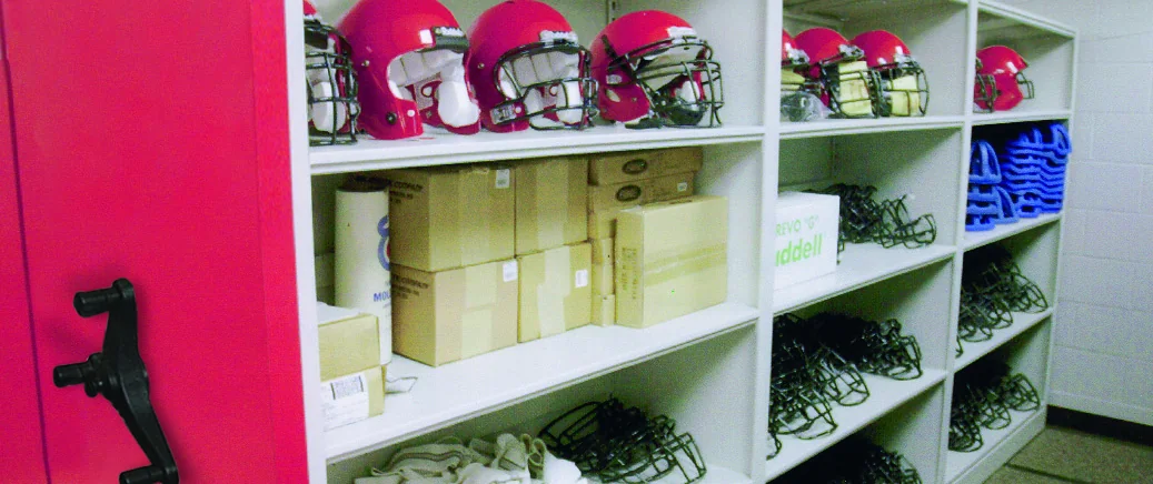 Aurora mobile shelving with a handwheel on a red end panel, storing football helmets, spare facemasks and boxed supplies