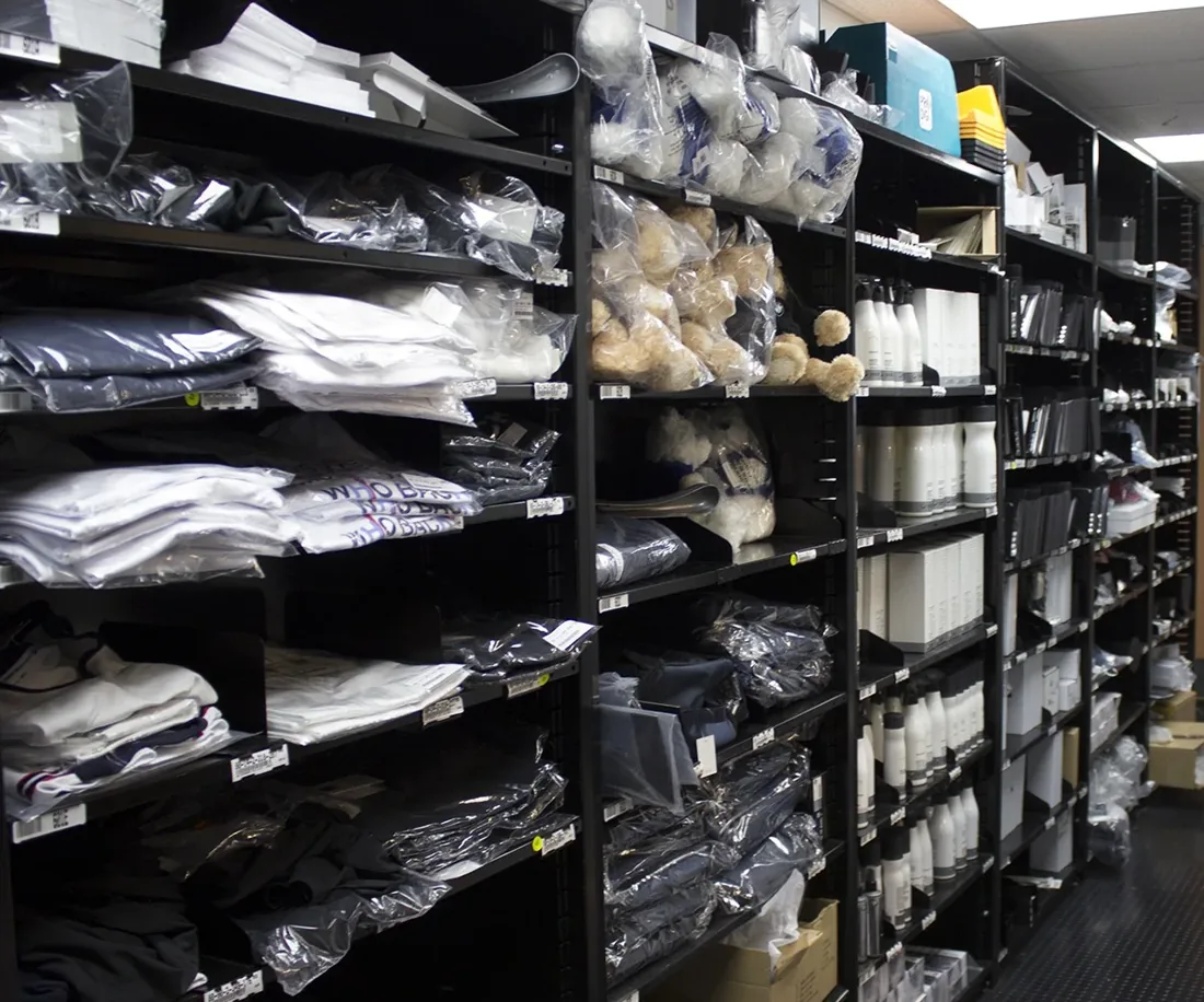 Black Borroughs Flexi-Bin shelving in a store back room holding apparel, accessories and boxed stock