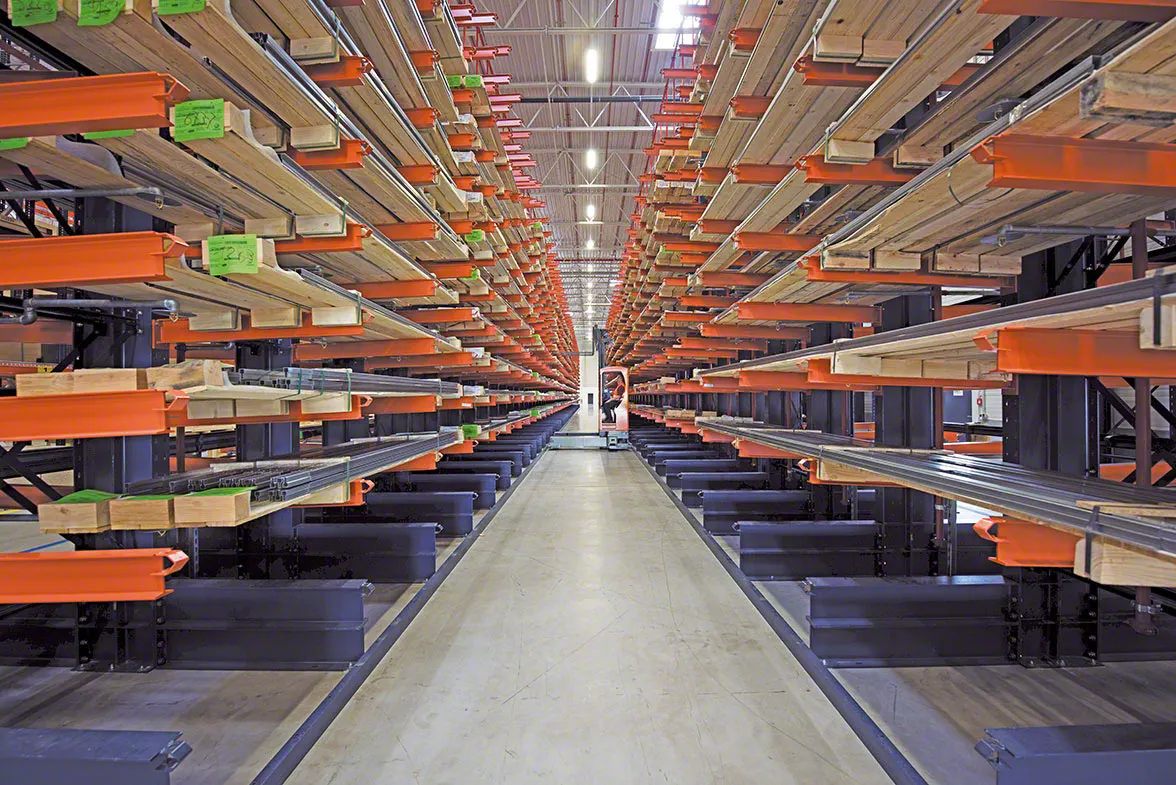 Warehouse aisle lined on both sides with cantilever racks storing lumber on orange arms