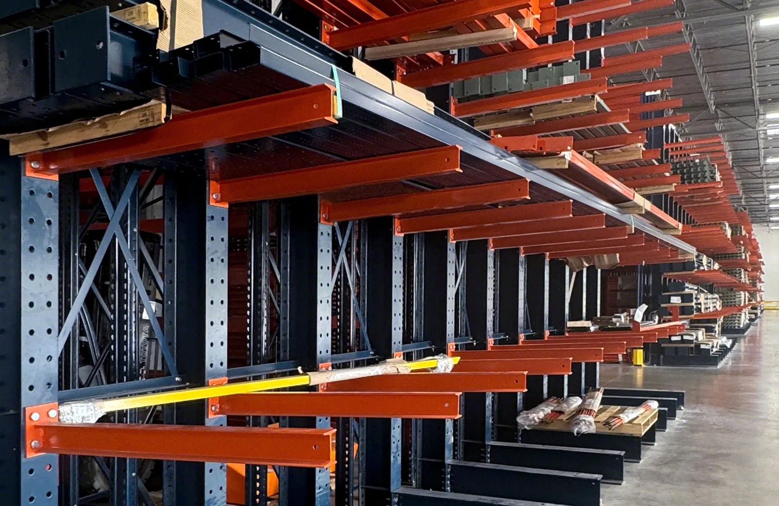 Row of cantilever rack columns with bolted orange arms, horizontal braces and X-bracing between uprights