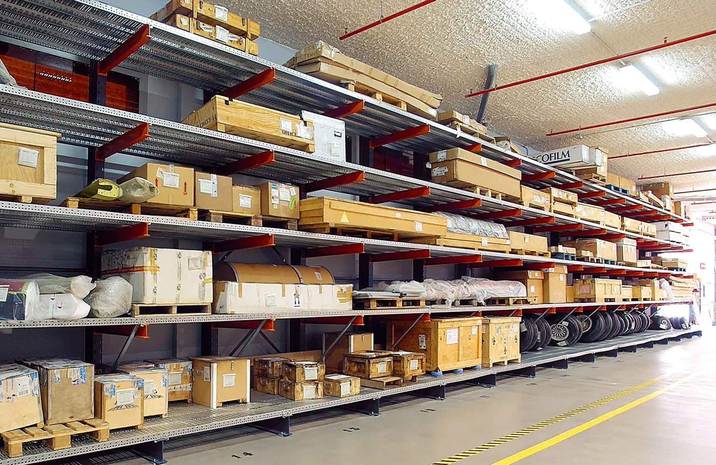 Single-sided cantilever rack with continuous steel decking holding crates, boxed stock and short panels