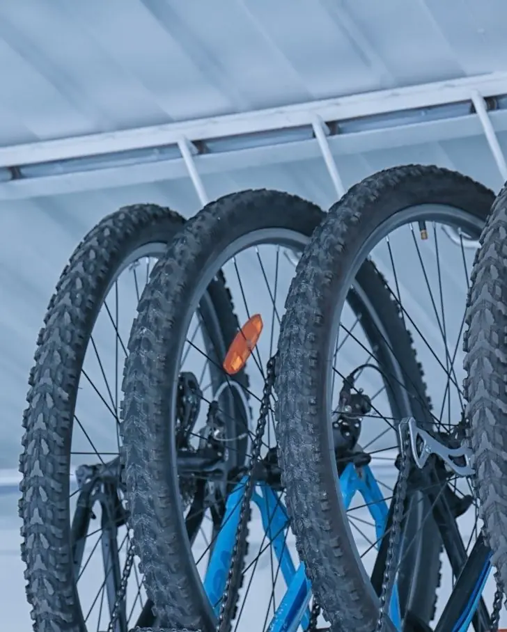 Mountain bikes hanging from hooks on a ceiling-mounted bike lift bar, stored overhead and off the floor