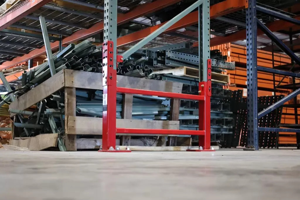 Red SpaceGuard Centurion Row Guard protecting front and rear uprights at the end of a pallet rack row