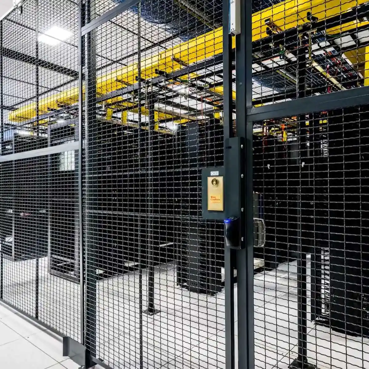 Wire mesh data center cage door with a lock box in front of server racks