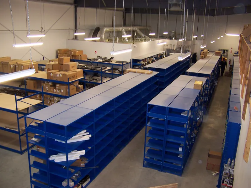 Dealership parts room with rows of low and full-height blue Equipto shelving loaded with boxed parts