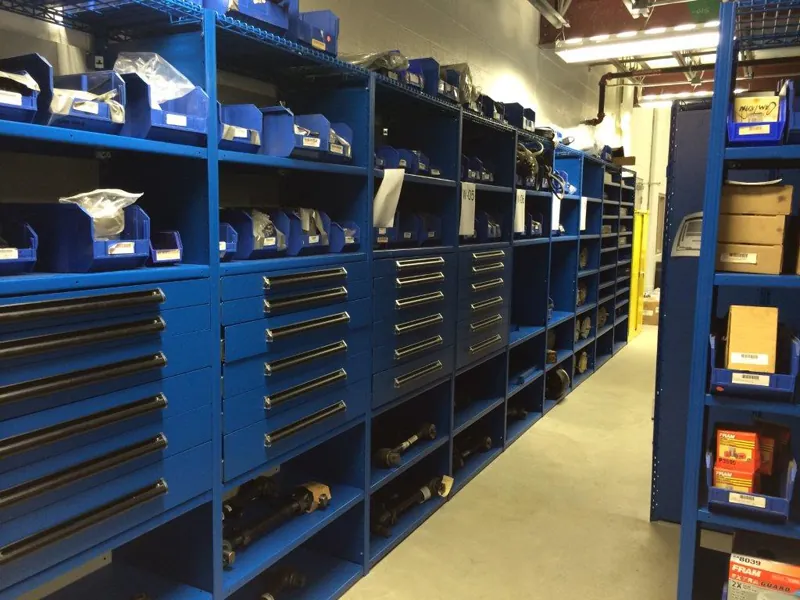 Blue Equipto V-Grip parts department shelving with modular drawers built into the bays and boxed parts on the shelves above