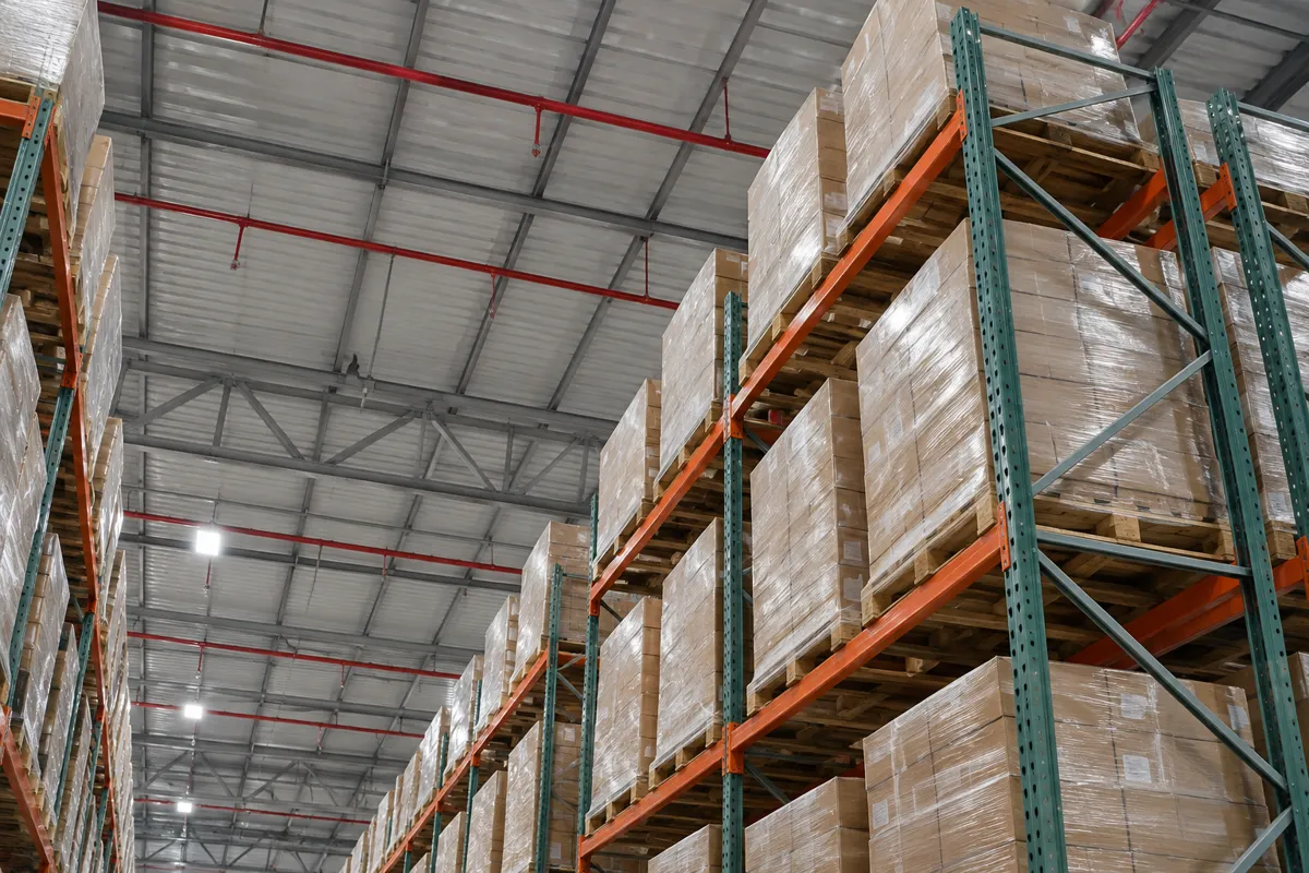 Top of loaded pallet racking with clear space below the ceiling fire sprinkler pipes in a high-bay warehouse