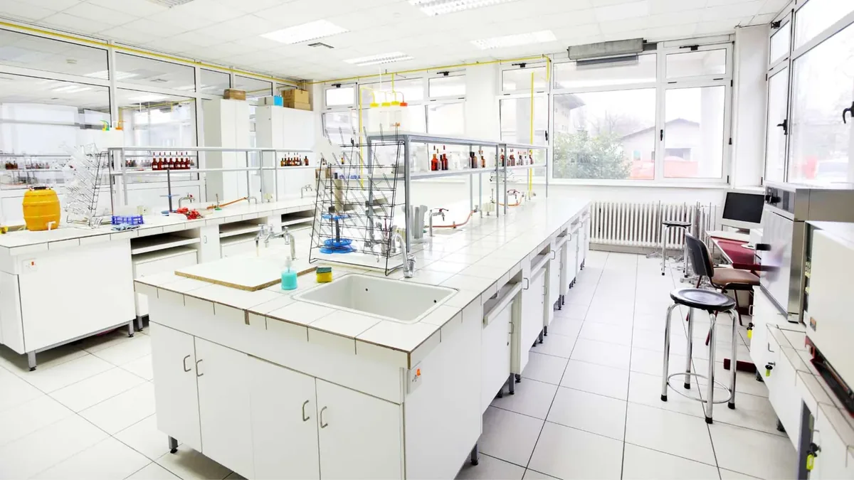 Bright laboratory with white island benches, sinks and glassware shelving