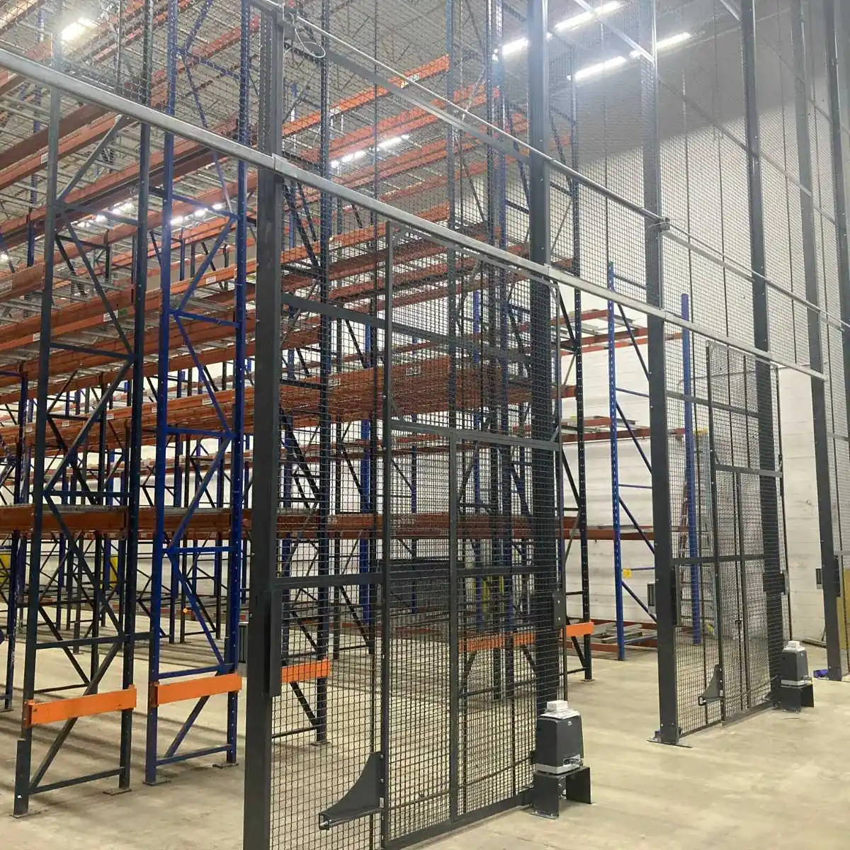 Large aerosol storage cage with a sliding mesh door along a pallet rack run