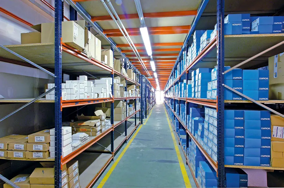 Long span shelving aisle with blue upright frames, orange beams and particleboard decks holding parts cartons on both sides