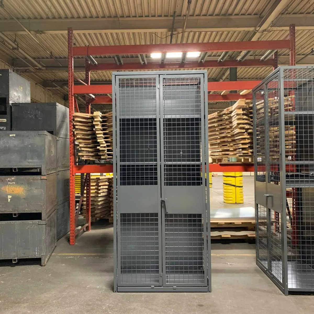 Gray military gear locker with wire mesh double doors in a warehouse