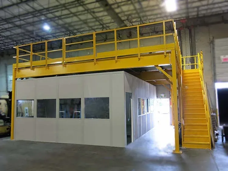 Modular in-plant office built under a yellow steel warehouse mezzanine with stairs